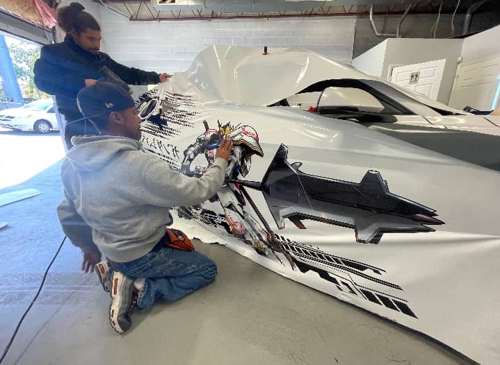 Installers applying custom graphic wrap panel in the shop